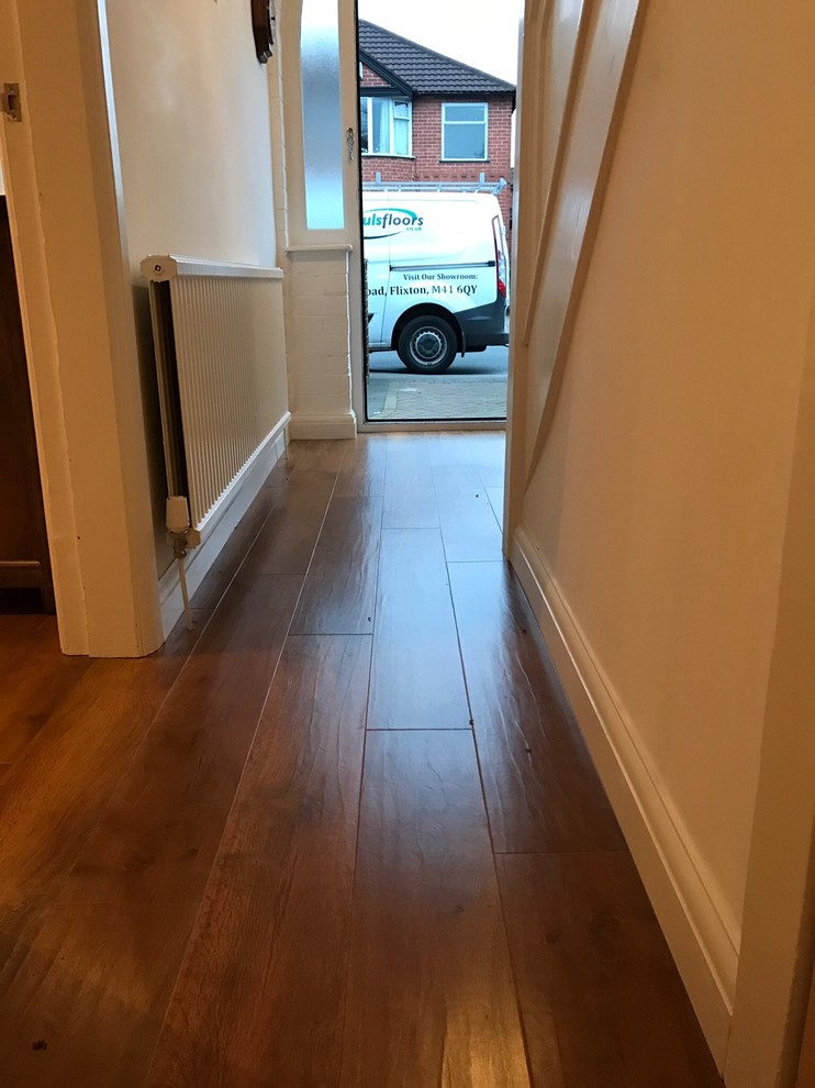 This is an example of a mid-sized contemporary enclosed living room in Manchester with white walls, vinyl floors and brown floor.