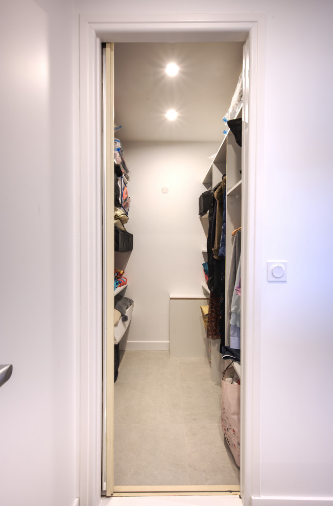 Design ideas for a medium sized modern gender neutral walk-in wardrobe in Montpellier with open cabinets, white cabinets and grey floors.