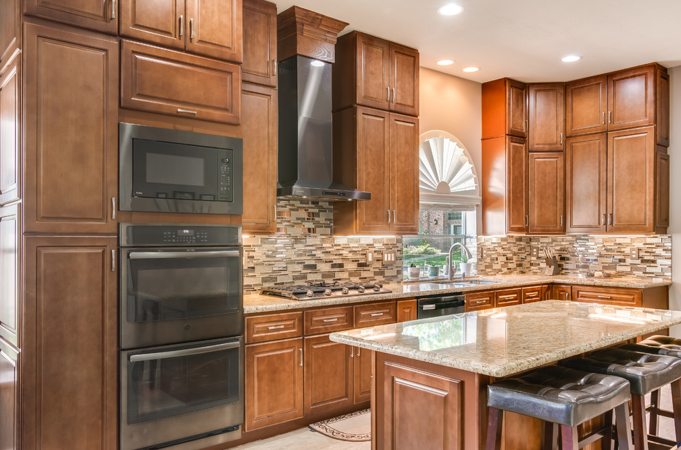 Large traditional l-shaped eat-in kitchen in Houston with a double-bowl sink, raised-panel cabinets, brown cabinets, granite benchtops, brown splashback, glass sheet splashback, black appliances, marble floors, with island, brown floor and brown benchtop.
