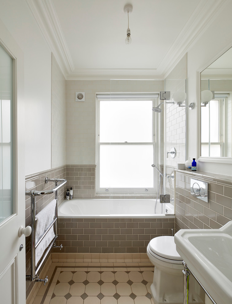 Design ideas for a small traditional master bathroom in London with a drop-in tub, a shower/bathtub combo, a one-piece toilet, gray tile, subway tile, white walls, ceramic floors, a console sink, beige floor, a hinged shower door, a single vanity and decorative wall panelling.