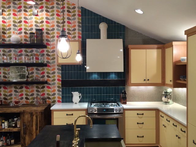 Inspiration for a mid-sized eclectic l-shaped eat-in kitchen in Nashville with a farmhouse sink, flat-panel cabinets, yellow cabinets, blue splashback, stainless steel appliances, medium hardwood floors, with island, solid surface benchtops and ceramic splashback.