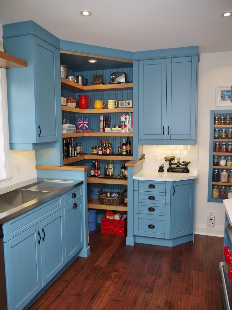 This is an example of a country kitchen in Toronto with an integrated sink, blue cabinets, stainless steel benchtops, white splashback, subway tile splashback, stainless steel appliances and open cabinets.