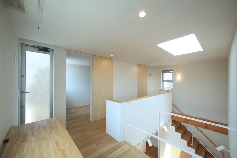 Modelo de recibidores y pasillos minimalistas pequeños con paredes blancas, suelo de madera clara, papel pintado y papel pintado