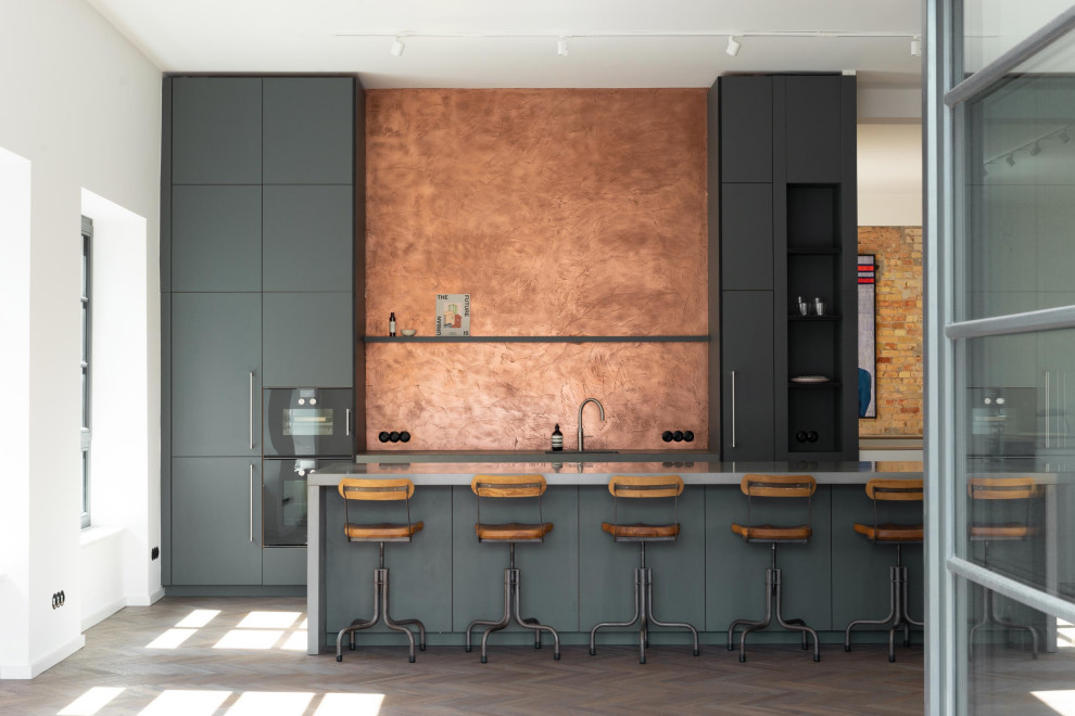 Inspiration for a large industrial single-wall eat-in kitchen in Berlin with a drop-in sink, flat-panel cabinets, grey cabinets, concrete benchtops, black appliances, dark hardwood floors, with island and grey benchtop.