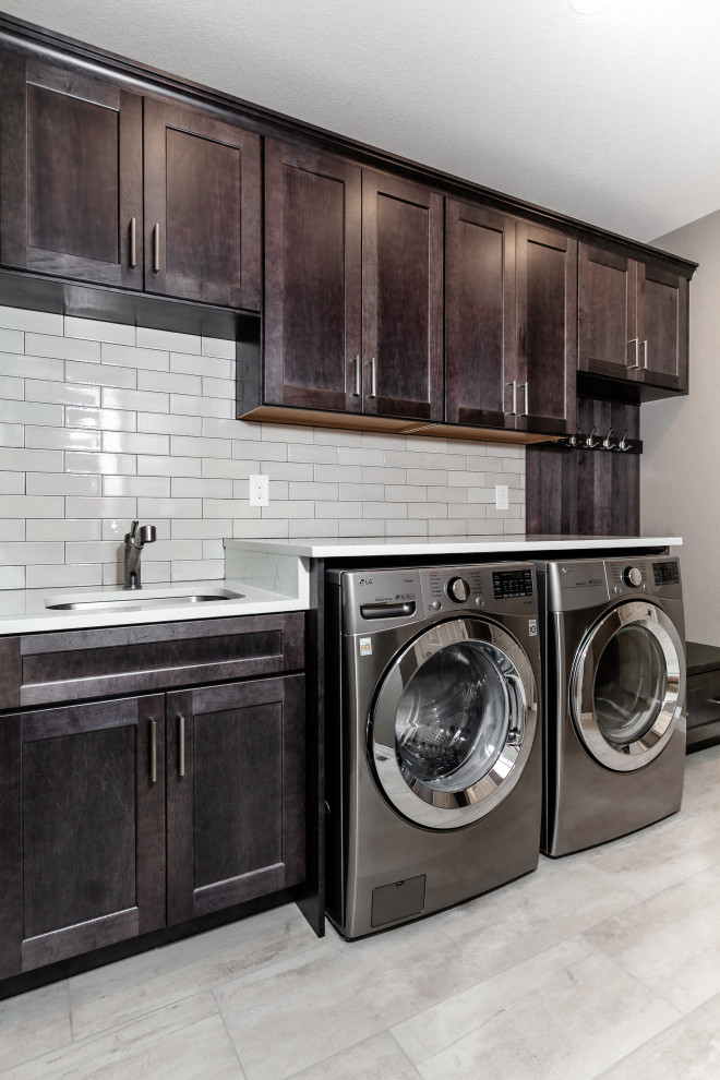 Design ideas for a traditional laundry room in Denver with a single-bowl sink, shaker cabinets, dark wood cabinets, quartz benchtops, beige splashback, ceramic splashback, beige walls, ceramic floors, a side-by-side washer and dryer, beige floor and white benchtop.