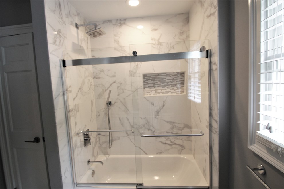 Photo of a mid-sized transitional kids bathroom in New York with flat-panel cabinets, white cabinets, an alcove tub, a two-piece toilet, black and white tile, ceramic tile, grey walls, porcelain floors, an undermount sink, quartzite benchtops, grey floor and a sliding shower screen.