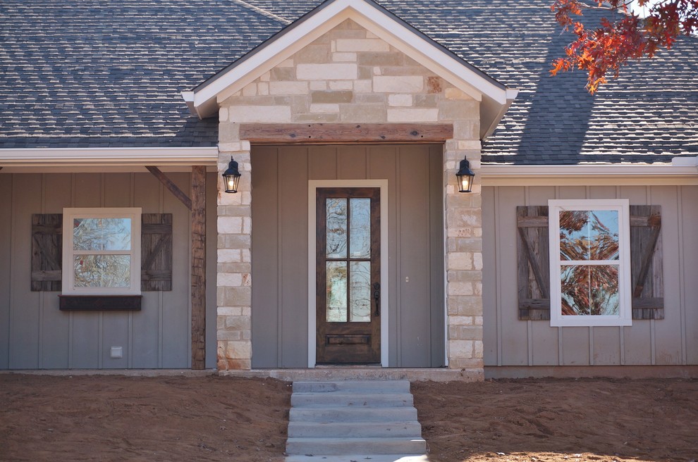 This is an example of a large country front door in Austin with grey walls, a single front door and a medium wood front door.