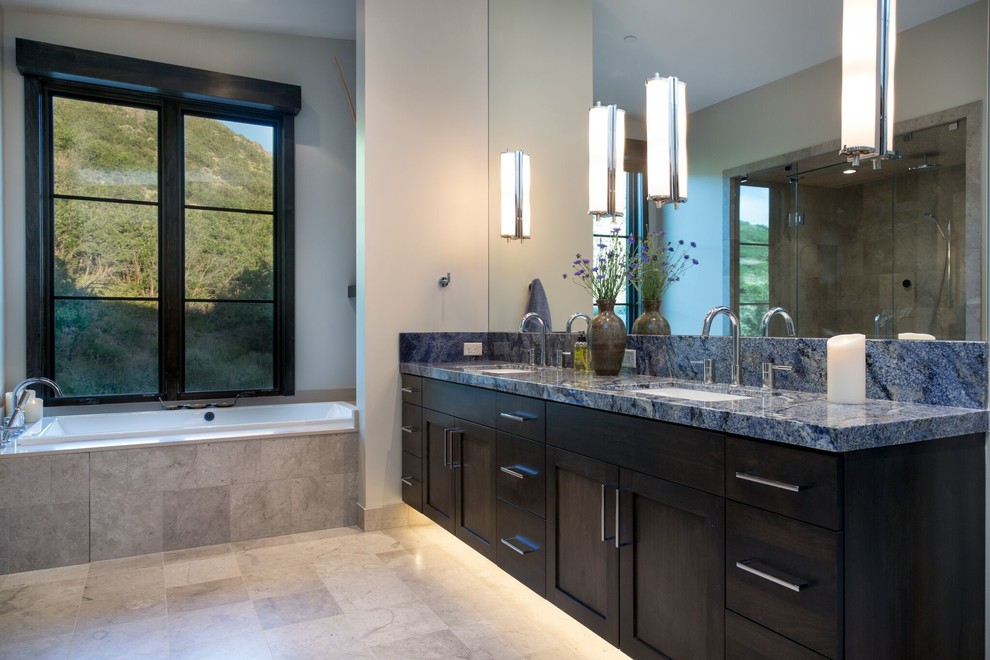 Inspiration for a large contemporary master bathroom in Salt Lake City with shaker cabinets, dark wood cabinets, a drop-in tub, beige tile, beige walls, an undermount sink, granite benchtops, beige floor, an alcove shower, porcelain tile, porcelain floors, a hinged shower door and blue benchtops.
