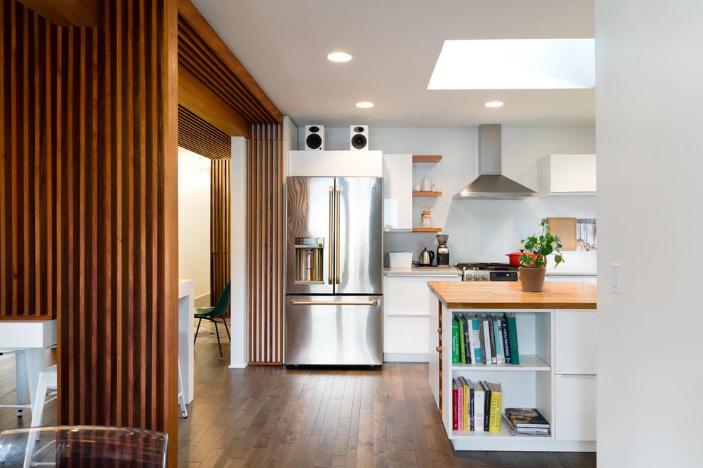 Mid-sized midcentury l-shaped open plan kitchen in Omaha with a double-bowl sink, flat-panel cabinets, white cabinets, laminate benchtops, white splashback, stainless steel appliances, dark hardwood floors, multiple islands and black floor.