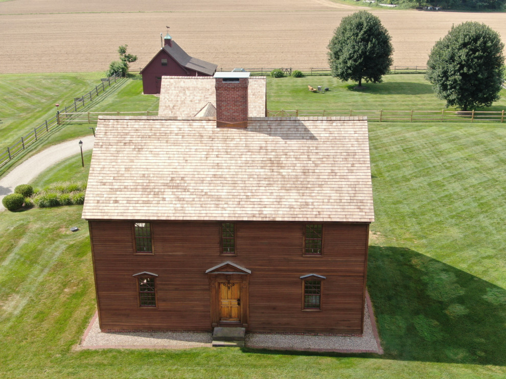Foto på ett stort lantligt brunt hus, med tre eller fler plan, sadeltak och tak i shingel