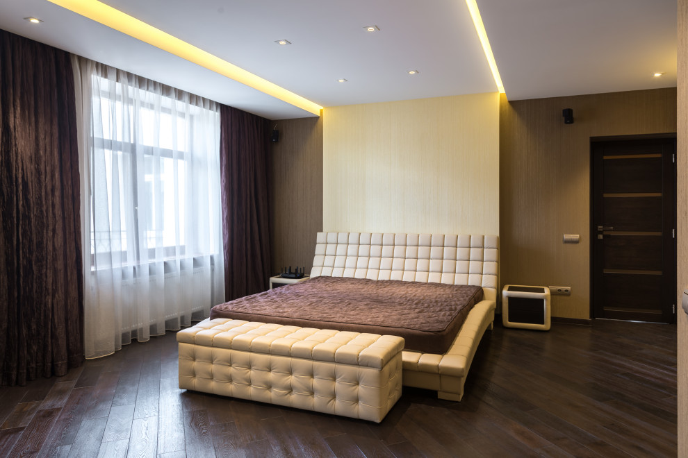 Пример оригинального дизайна: большая хозяйская спальня: освещение с желтыми стенами, темным паркетным полом, коричневым полом и многоуровневым потолком
