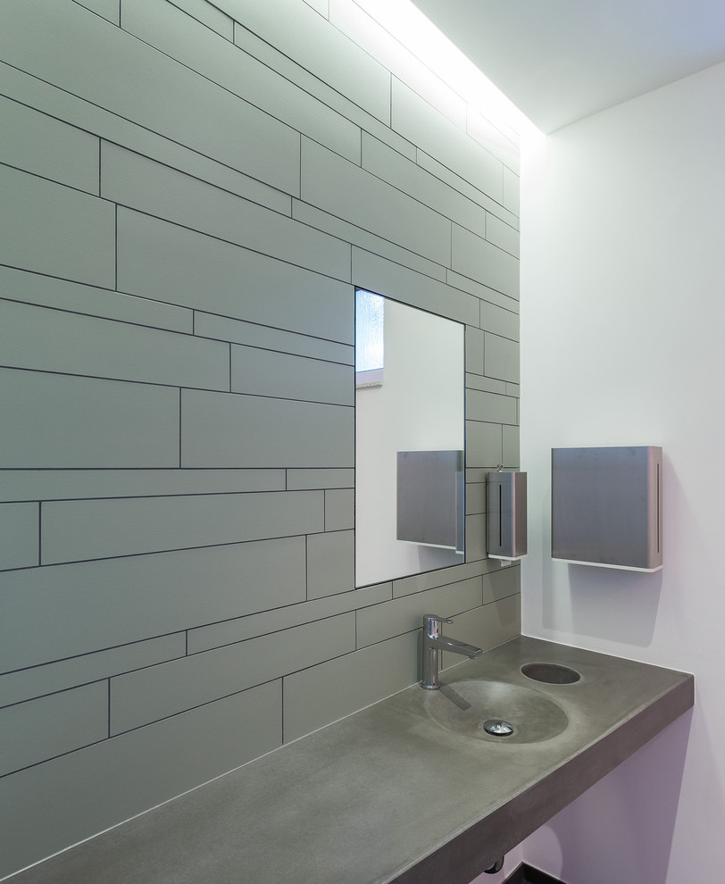 Gästetoilette mit Wandtoilette, grünen Fliesen, Steinfliesen, weißer Wandfarbe, Keramikboden, Beton-Waschbecken/Waschtisch und integriertem Waschbecken in Cologne