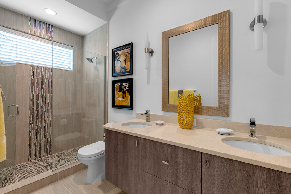 Photo of a small modern 3/4 bathroom in Orlando with flat-panel cabinets, medium wood cabinets, an alcove shower, a two-piece toilet, multi-coloured tile, glass tile, white walls, porcelain floors, a drop-in sink and engineered quartz benchtops.