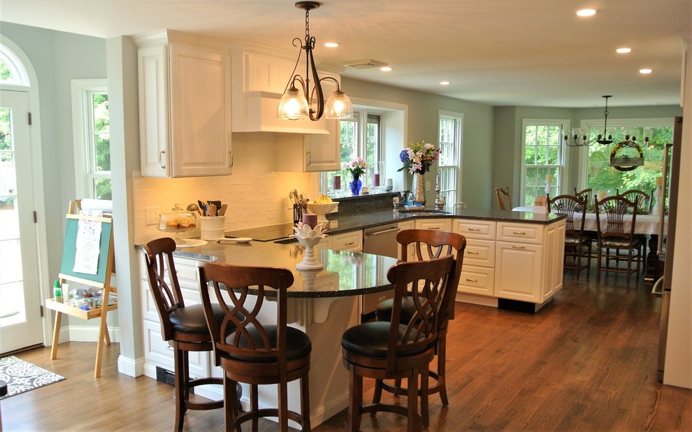 Inspiration for a transitional light wood floor eat-in kitchen remodel in Boston with an undermount sink, raised-panel cabinets, white cabinets, granite countertops, white backsplash, subway tile backsplash and stainless steel appliances