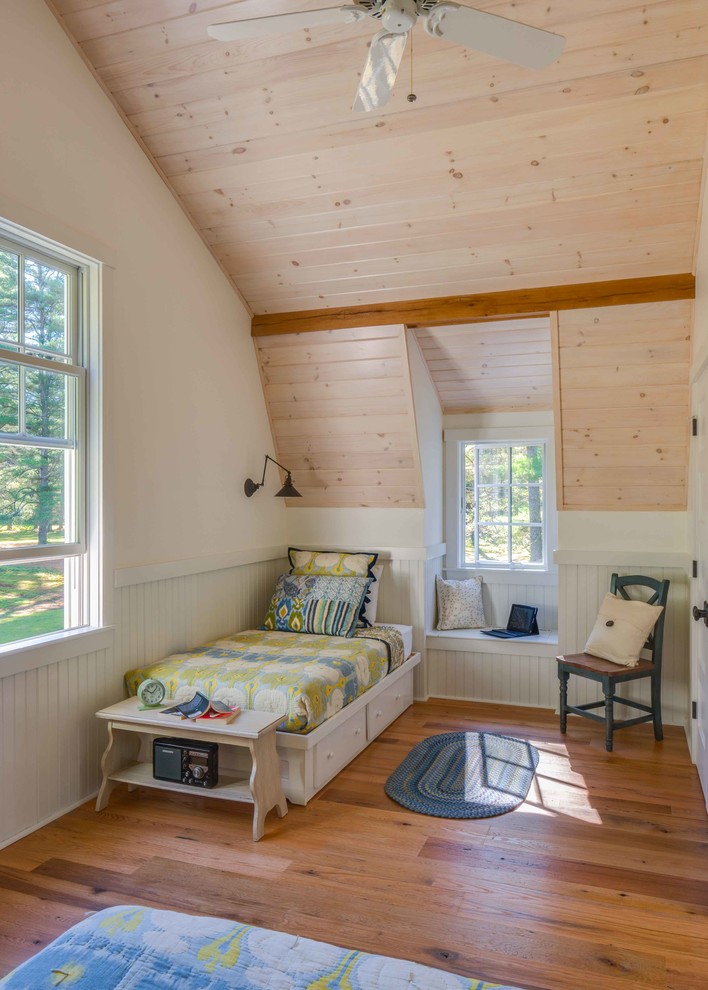 This is an example of a traditional guest bedroom in Portland Maine with white walls and medium hardwood floors.