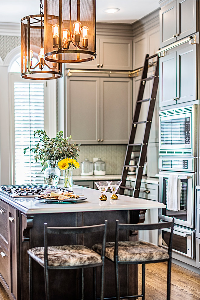 Example of a large transitional u-shaped medium tone wood floor and brown floor enclosed kitchen design in Nashville with an undermount sink, recessed-panel cabinets, gray cabinets, granite countertops, white backsplash, mosaic tile backsplash, stainless steel appliances, an island and multicolored countertops
