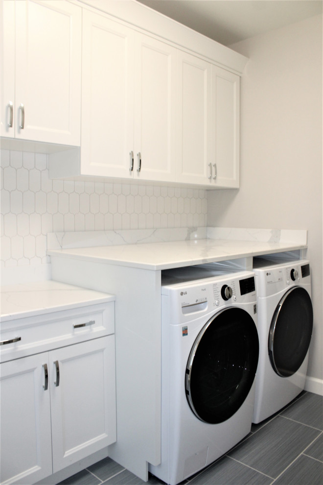 Mid-sized single-wall dedicated laundry room in Detroit with an undermount sink, recessed-panel cabinets, white cabinets, quartz benchtops, white splashback, ceramic splashback, grey walls, porcelain floors, a side-by-side washer and dryer, grey floor and white benchtop.