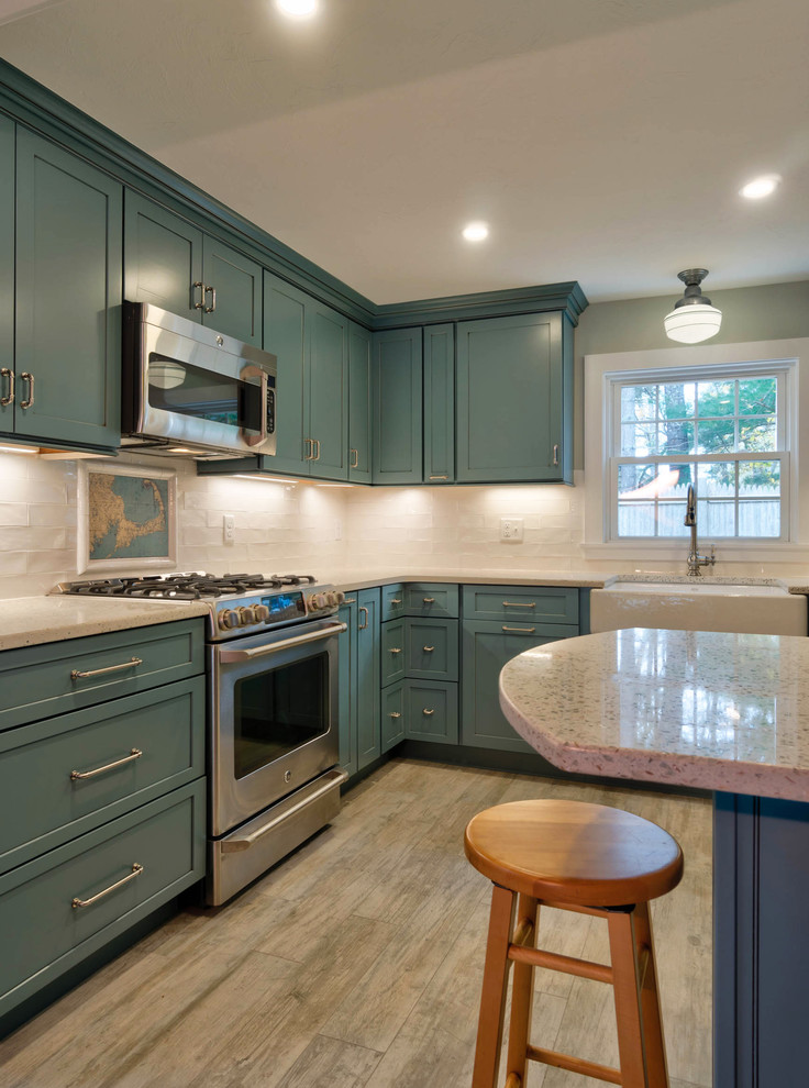 Inspiration for a small modern l-shaped kitchen pantry in Boston with a farmhouse sink, shaker cabinets, blue cabinets, recycled glass benchtops, white splashback, ceramic splashback, stainless steel appliances, ceramic floors, with island and beige floor.