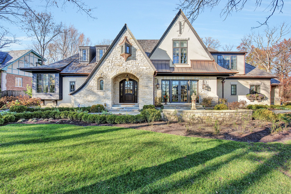 Inspiration for a large traditional two-storey stucco beige house exterior in Chicago with a gable roof and a mixed roof.
