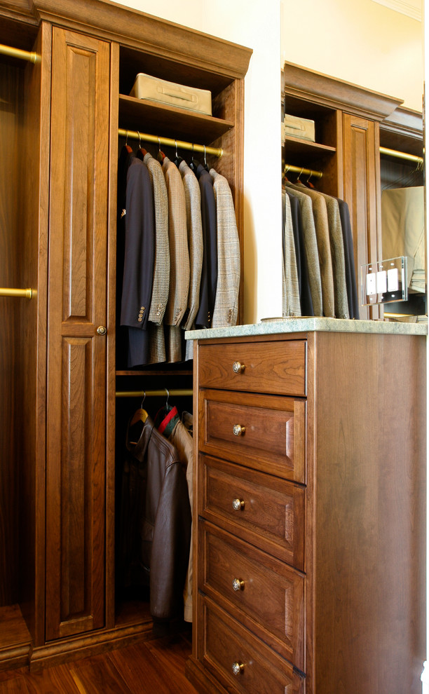 Photo of a mid-sized traditional men's walk-in wardrobe in Louisville with raised-panel cabinets, medium wood cabinets, medium hardwood floors and brown floor.