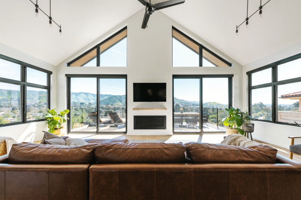 Photo of a large modern open plan living room in San Luis Obispo with white walls, light hardwood flooring, a ribbon fireplace, a built-in media unit, brown floors and a vaulted ceiling.