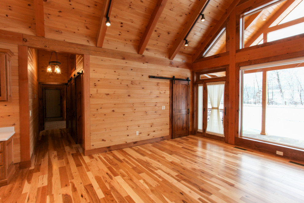 Example of a mountain style light wood floor, yellow floor, wood ceiling and wood wall foyer design with a glass front door