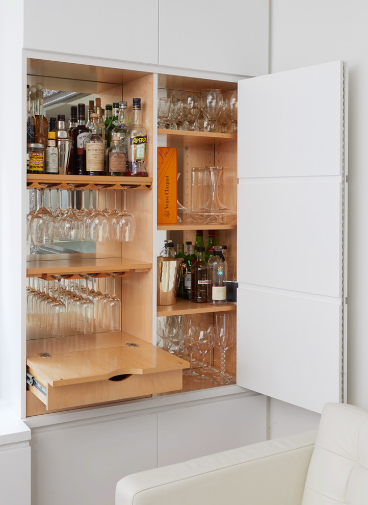Design ideas for a small contemporary home bar in New York with no sink, flat-panel cabinets, white cabinets, wood benchtops and mirror splashback.