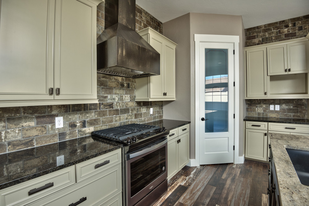 Mid-sized traditional l-shaped open plan kitchen in Other with an undermount sink, recessed-panel cabinets, beige cabinets, laminate benchtops, grey splashback, brick splashback, stainless steel appliances, medium hardwood floors, with island, multi-coloured floor and multi-coloured benchtop.