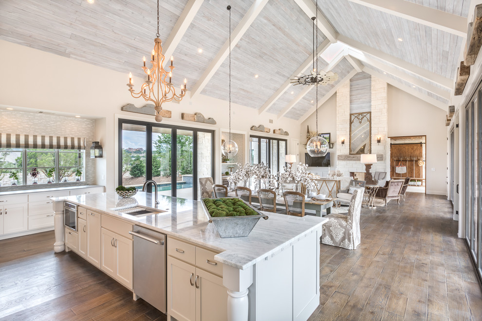 Design ideas for a country open plan kitchen in Austin with an undermount sink, shaker cabinets, white cabinets, stainless steel appliances, dark hardwood floors, with island and brown floor.
