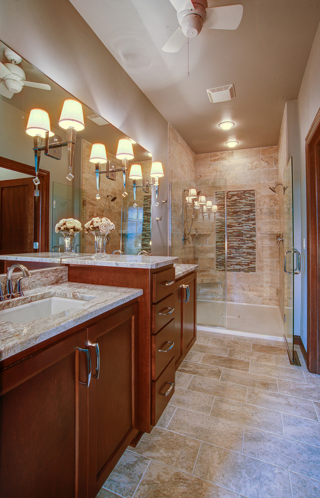 Photo of a large transitional master bathroom in Milwaukee with shaker cabinets, brown cabinets, a freestanding tub, an alcove shower, blue tile, gray tile, white tile, stone tile, green walls, travertine floors, an undermount sink, granite benchtops, beige floor and a hinged shower door.
