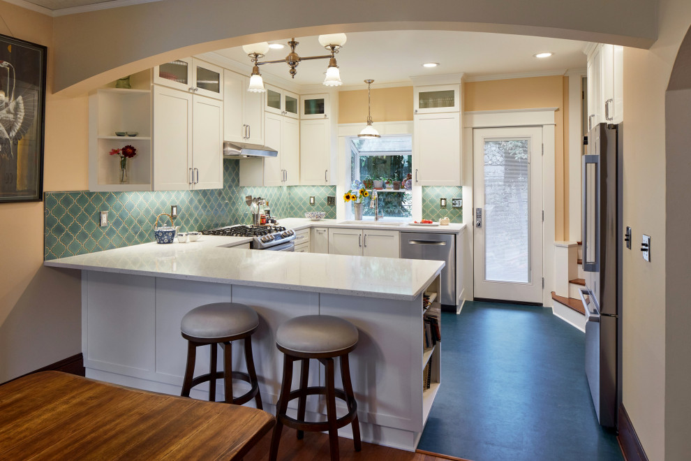 Photo of a mid-sized transitional u-shaped eat-in kitchen in Portland with an undermount sink, shaker cabinets, white cabinets, blue splashback, stainless steel appliances and white benchtop.