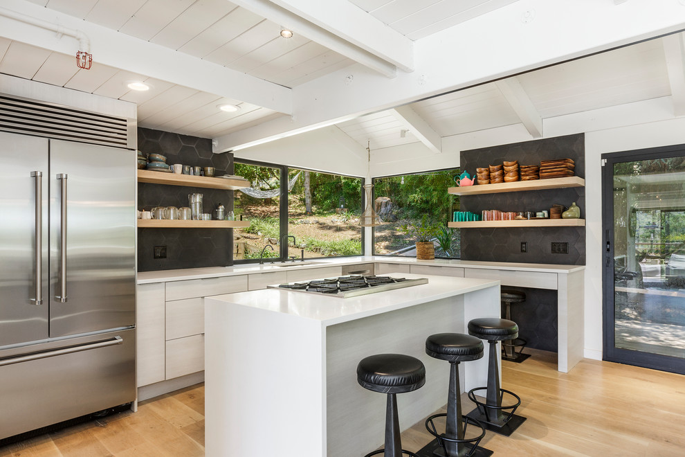 This is an example of a contemporary l-shaped kitchen in San Francisco with an undermount sink, flat-panel cabinets, grey cabinets, stainless steel appliances, medium hardwood floors, with island, brown floor and white benchtop.