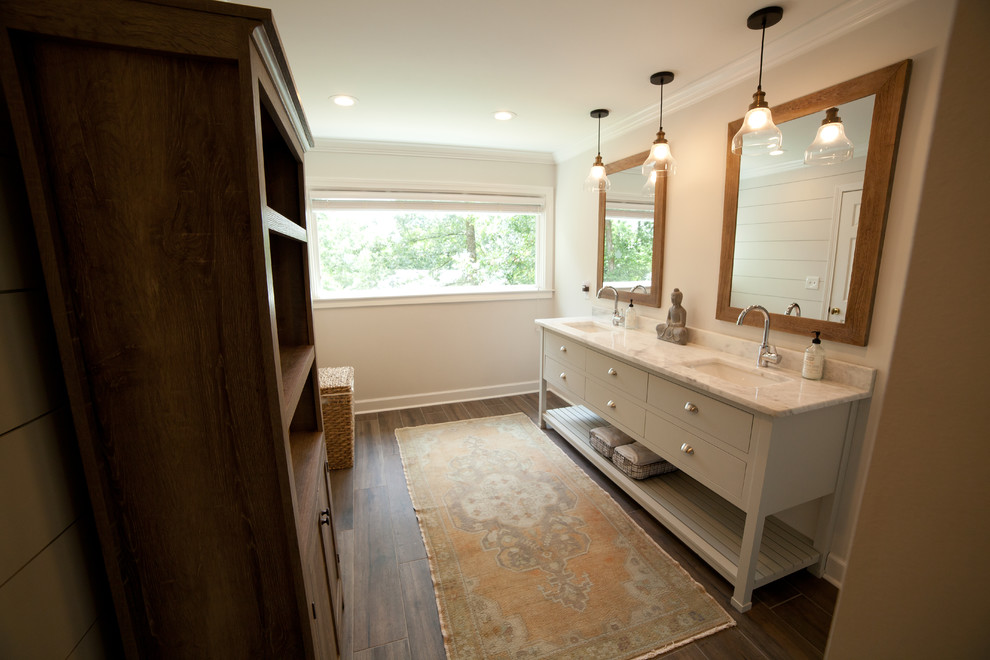 Photo of a large modern master bathroom in Atlanta with furniture-like cabinets, white cabinets, a corner shower, a one-piece toilet, white tile, subway tile, grey walls, dark hardwood floors, an undermount sink, marble benchtops, brown floor and a hinged shower door.