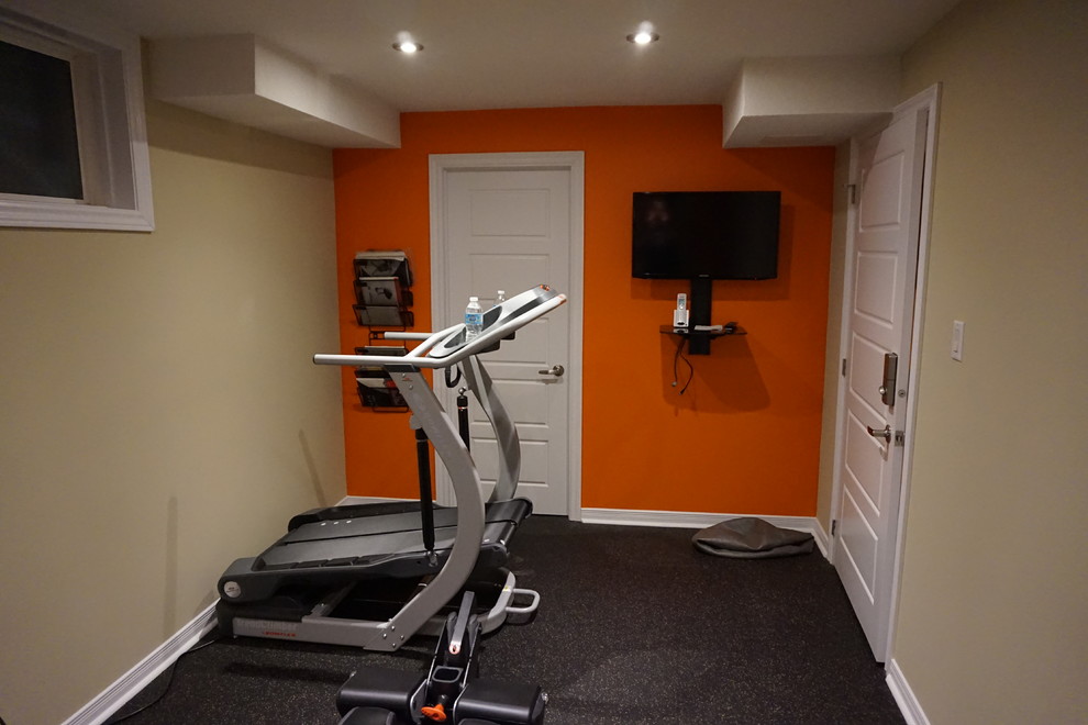 This is an example of a mid-sized modern home weight room in Toronto with beige walls and black floor.