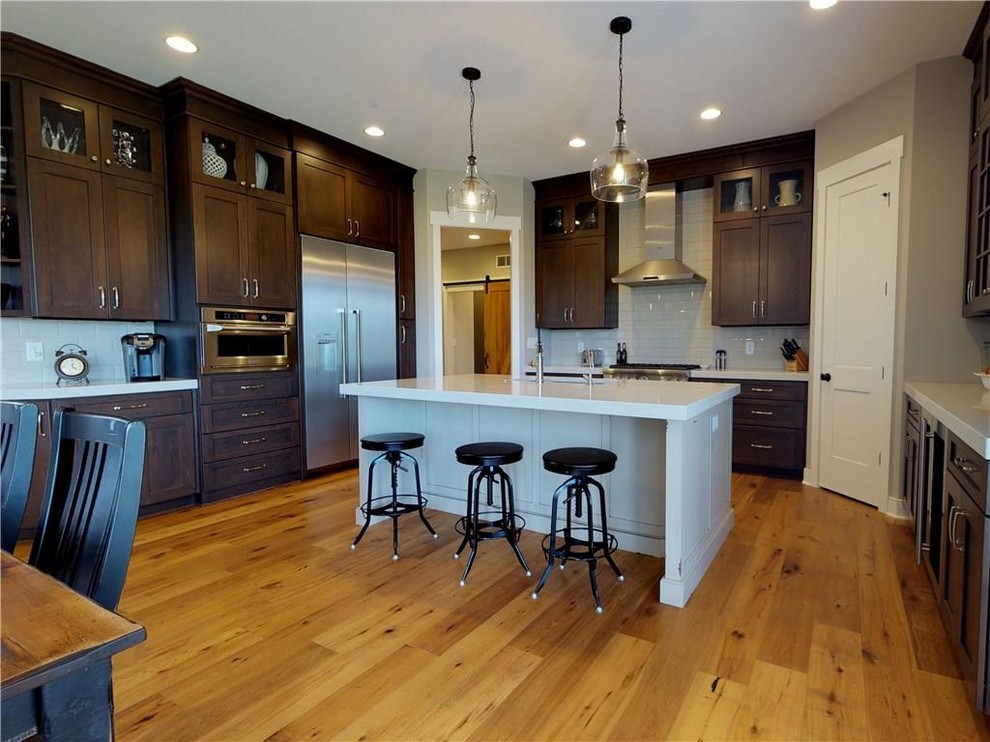 Example of a transitional light wood floor eat-in kitchen design in Indianapolis with an undermount sink, flat-panel cabinets, medium tone wood cabinets, quartz countertops, white backsplash, subway tile backsplash, stainless steel appliances and an island