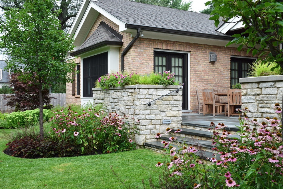 Inspiration for a mid-sized traditional backyard full sun garden for summer in Chicago with natural stone pavers.