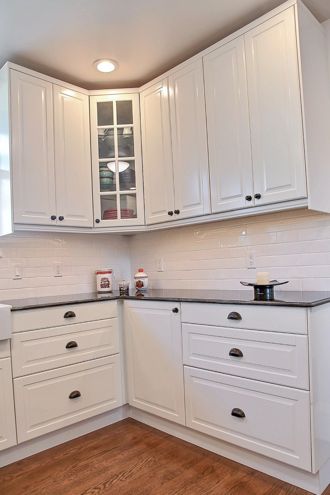 Mid-sized traditional kitchen pantry in San Francisco with a farmhouse sink, recessed-panel cabinets, white cabinets, white splashback, stainless steel appliances, medium hardwood floors and no island.