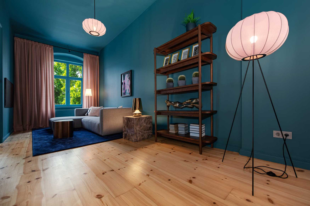 Kleines, Abgetrenntes Eklektisches Wohnzimmer mit blauer Wandfarbe, hellem Holzboden und TV-Wand in Berlin