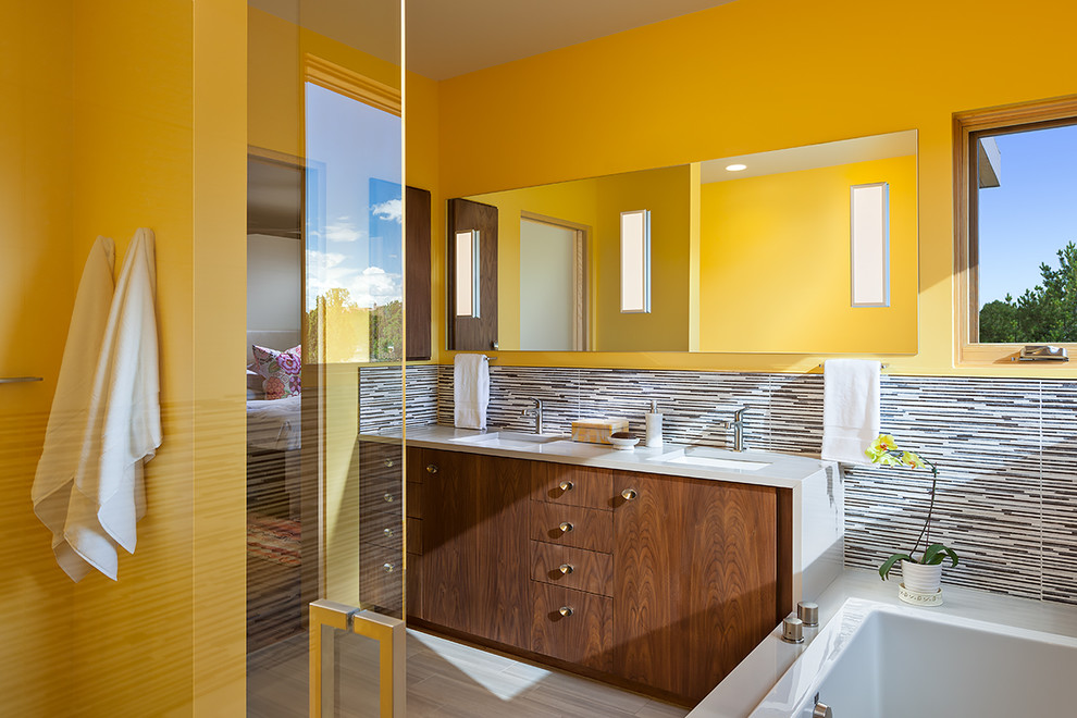 Photo of a mid-sized contemporary master bathroom in Albuquerque with flat-panel cabinets, medium wood cabinets, a drop-in tub, a corner shower, matchstick tile, yellow walls, porcelain floors, an undermount sink, quartzite benchtops and multi-coloured tile.