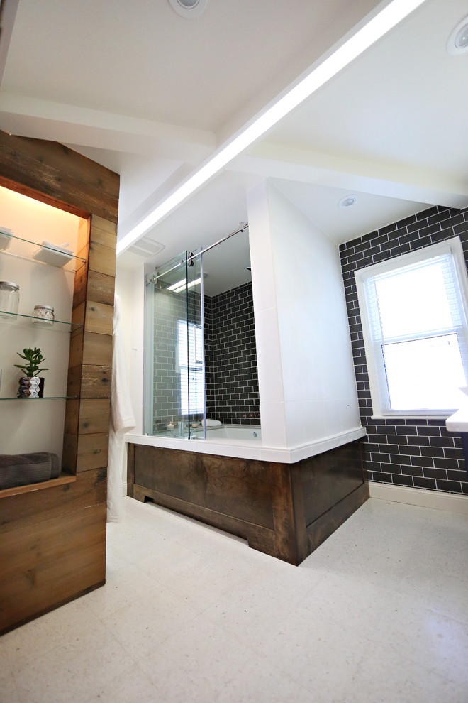 Design ideas for a large contemporary master bathroom in Minneapolis with a vessel sink, recessed-panel cabinets, black cabinets, marble benchtops, a drop-in tub, a shower/bathtub combo, a one-piece toilet, glass tile, black tile, white walls and beige floor.