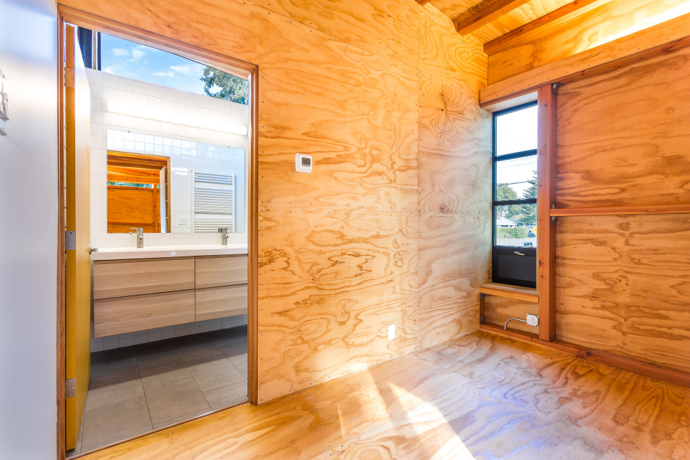 Foto di una camera matrimoniale minimalista di medie dimensioni con pavimento in cemento, travi a vista e pareti in legno