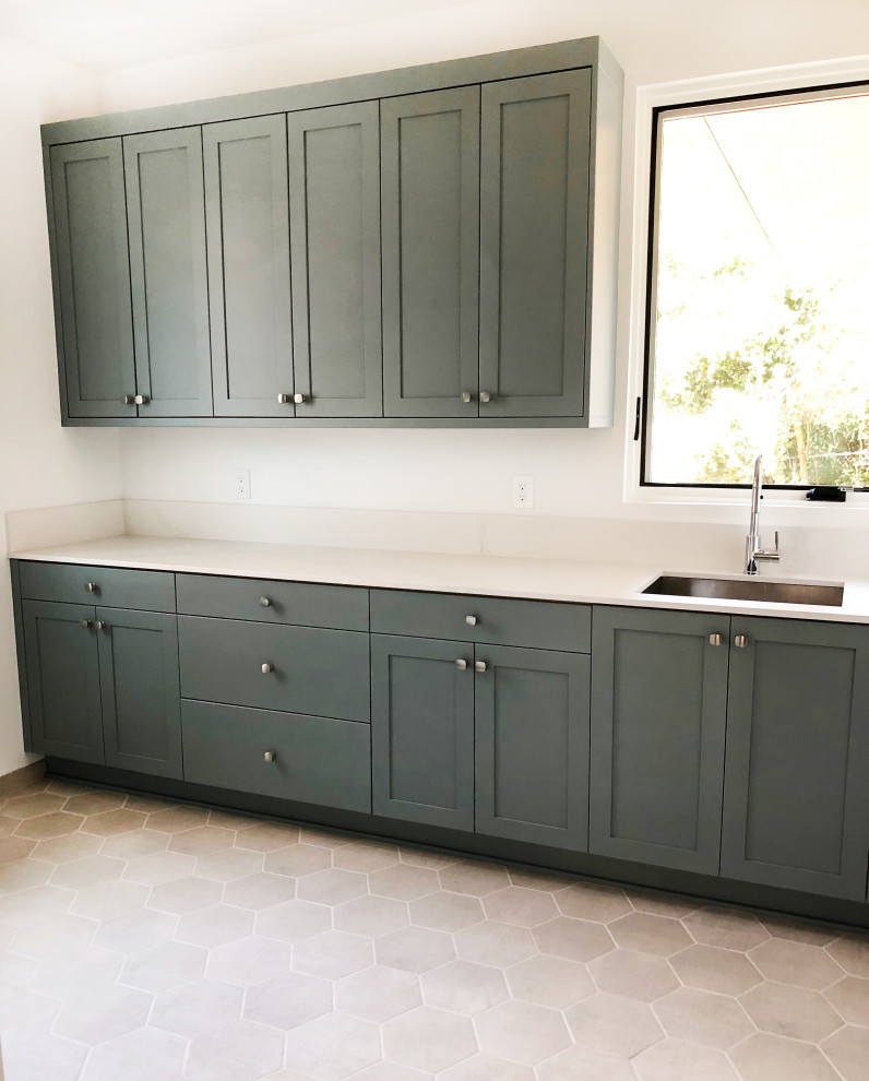 Inspiration for a large contemporary single-wall dedicated laundry room in Santa Barbara with an undermount sink, shaker cabinets, green cabinets, quartz benchtops, white splashback, engineered quartz splashback, white walls, ceramic floors, beige floor and white benchtop.