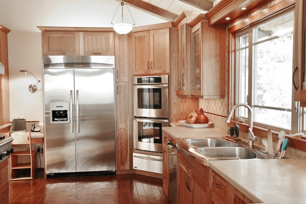 Example of a mid-sized transitional l-shaped medium tone wood floor enclosed kitchen design in San Francisco with an undermount sink, shaker cabinets, medium tone wood cabinets, granite countertops, beige backsplash, stone tile backsplash and stainless steel appliances