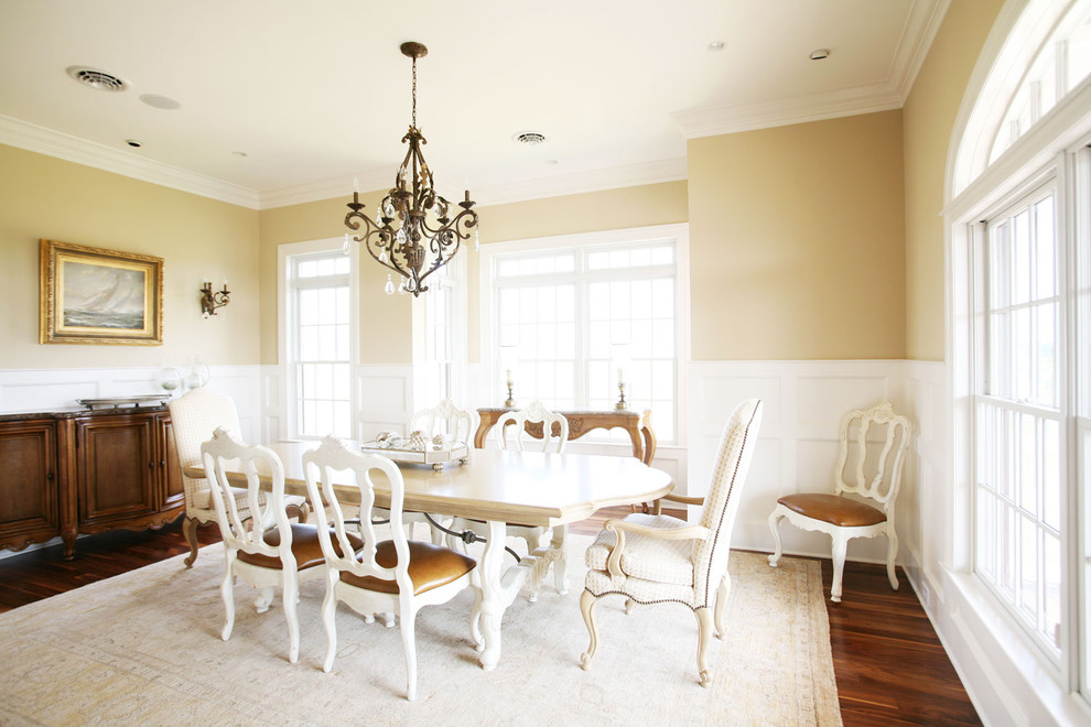 Traditional dining room in Other with yellow walls and dark hardwood floors.