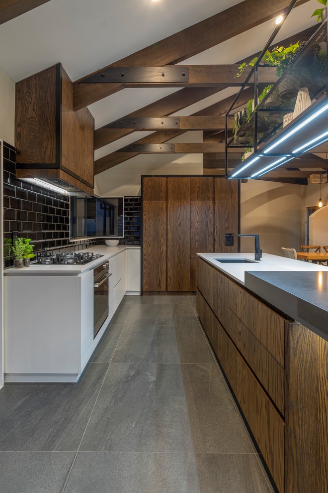 Mid-sized contemporary l-shaped eat-in kitchen in Auckland with dark wood cabinets, quartz benchtops, black splashback, subway tile splashback, with island and white benchtop.