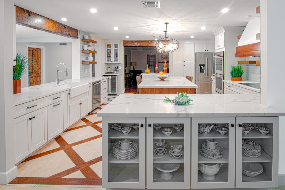 Photo of a mid-sized transitional eat-in kitchen in Phoenix with travertine floors, beige floor, a farmhouse sink, shaker cabinets, white cabinets, grey splashback, subway tile splashback, stainless steel appliances, with island and white benchtop.