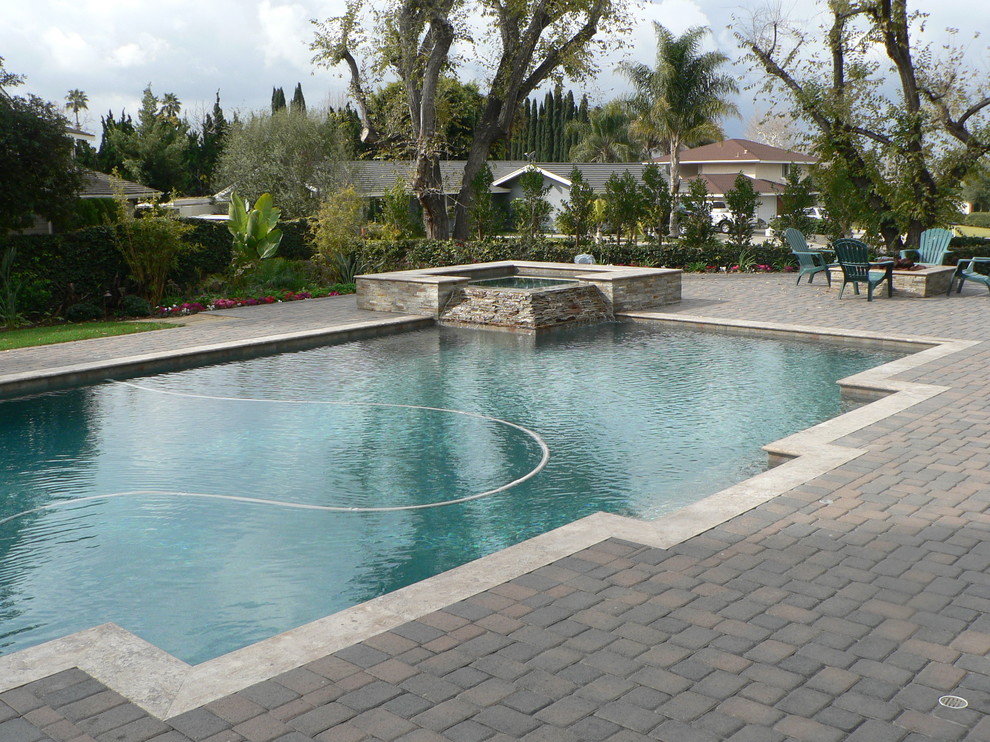Inspiration for a large mediterranean backyard rectangular lap pool in Orange County with concrete pavers and a hot tub.