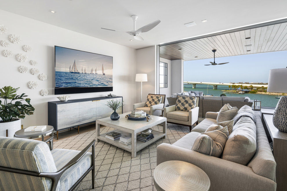 Inspiration for a small beach style open concept living room in Tampa with white walls, light hardwood floors, a wall-mounted tv and beige floor.