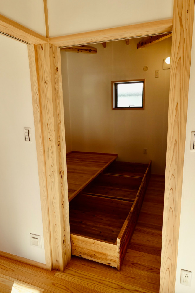 Foto de dormitorio principal y beige con paredes blancas, suelo de madera en tonos medios, suelo beige, techo inclinado y papel pintado
