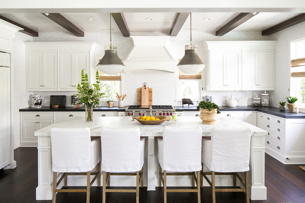 This is an example of a country l-shaped kitchen in Orange County with with island, shaker cabinets, white cabinets, white splashback, subway tile splashback, stainless steel appliances, dark hardwood floors and brown floor.